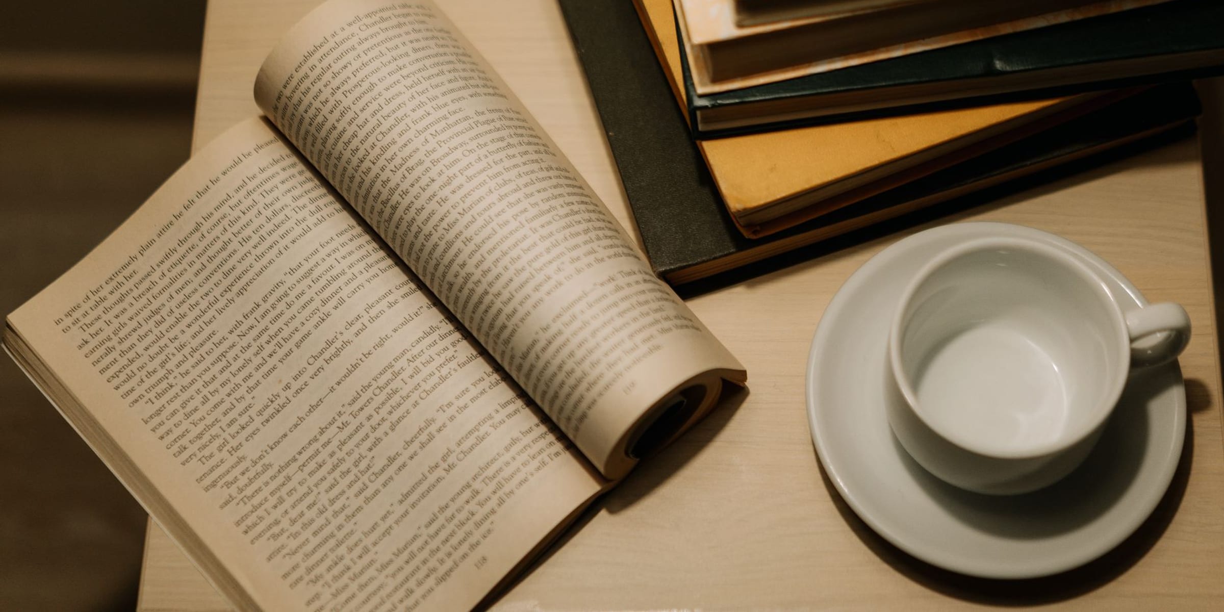 An open book resting on a warm wooden desk in soft daylight — a calm, focused reading space
